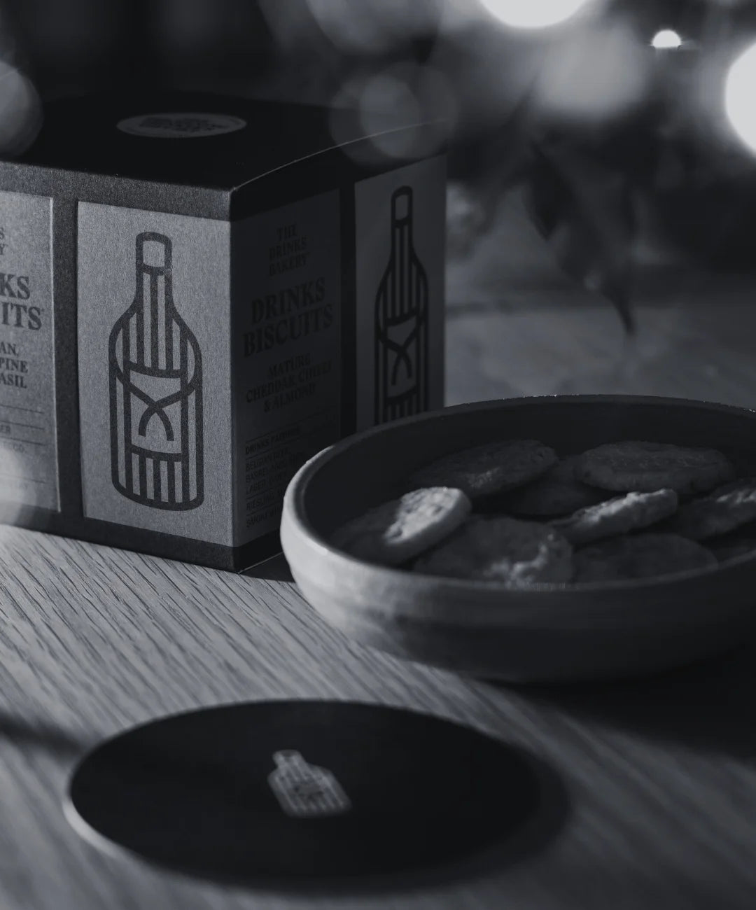 Box of savoury biscuits with a bowl of biscuits on a table, blurred lights in the background.