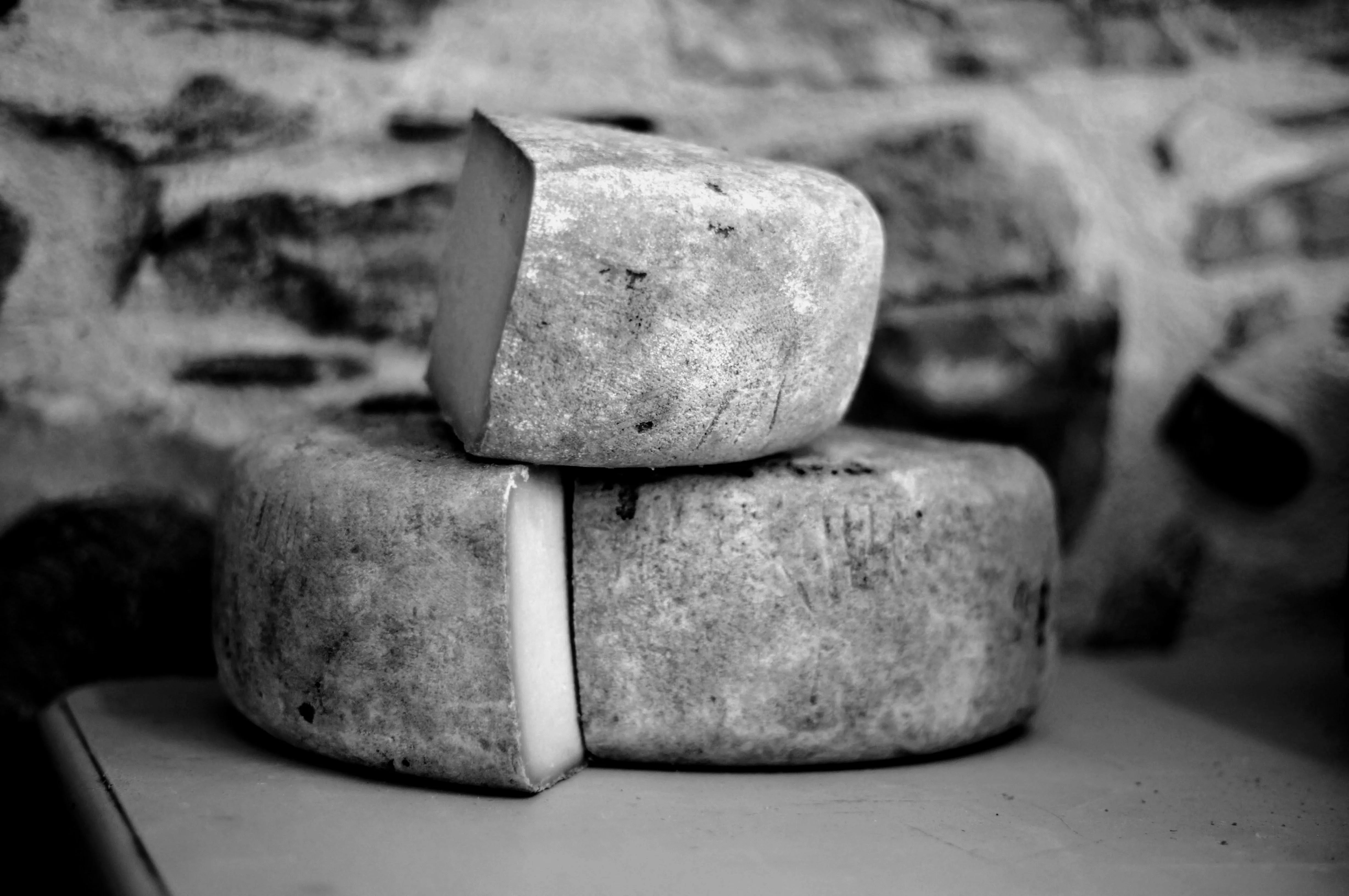 Two stacked pieces of cheese on a rustic stone surface